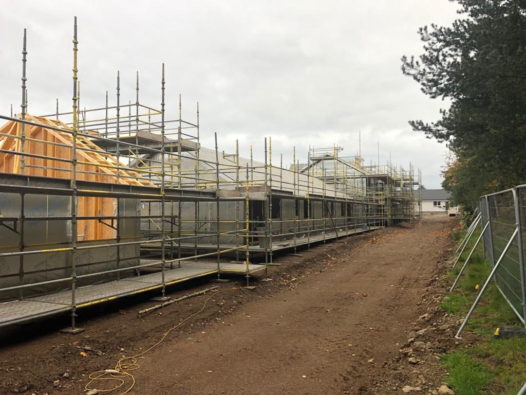 A terrace of timber-frame homes under construction behind scaffolding on a Perthshire site