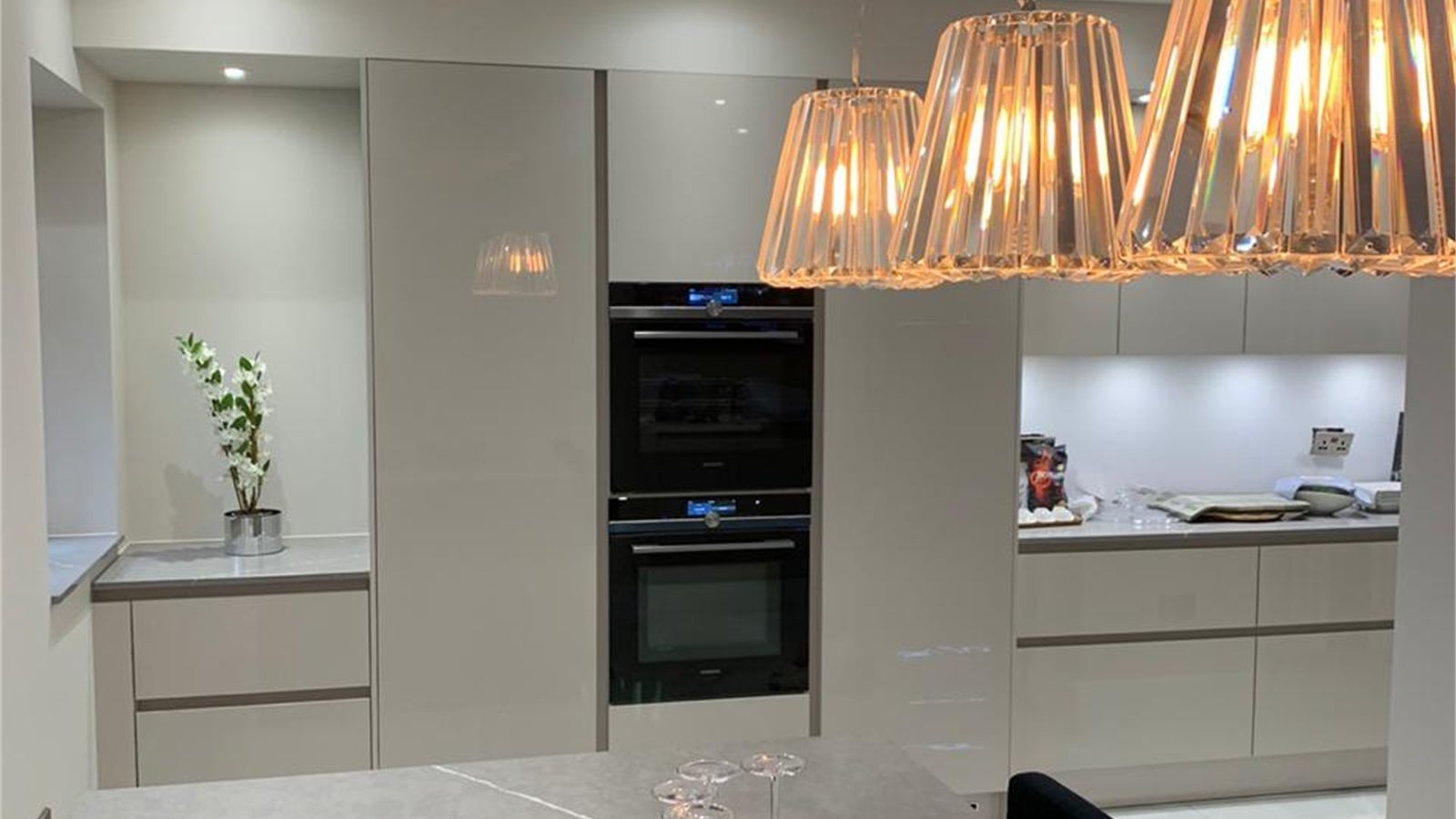 The kitchen, with a stone island, integrated appliances and pendant lighting over the run